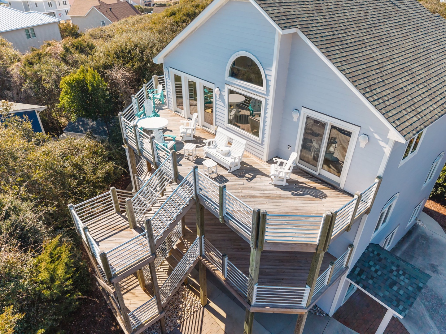 Aerial view of beach house featuring expansive multi-level deck with outdoor dining area and coastal neighborhood surroundings.