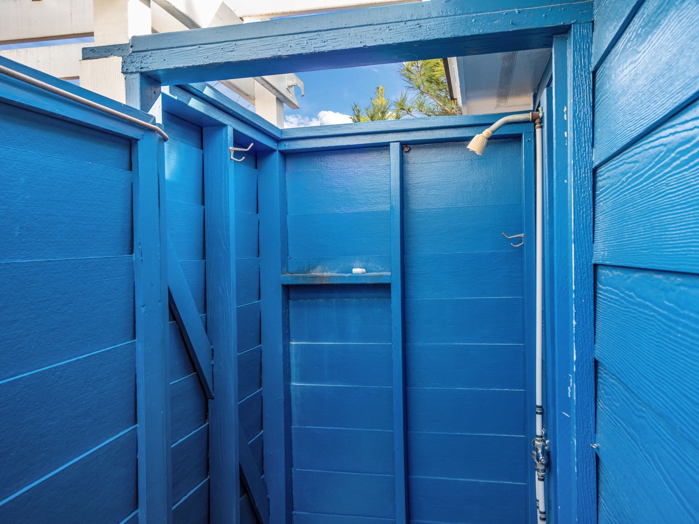 Rinse off after beach days in your private outdoor shower, surrounded by cheerful blue walls with open sky above.