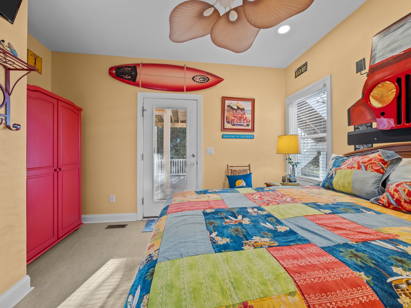 Your vibrant beach-themed bedroom features surf decor, colorful quilts, and tropical ceiling fans for the perfect coastal getaway vibe.