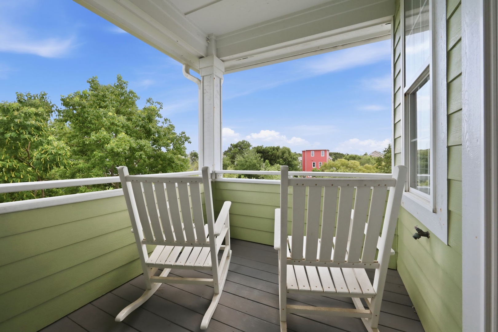 Settle into your private covered balcony with rocking chairs, where leafy treetops and blue skies create a peaceful retreat to sip morning coffee or unwind after exploring the area.
