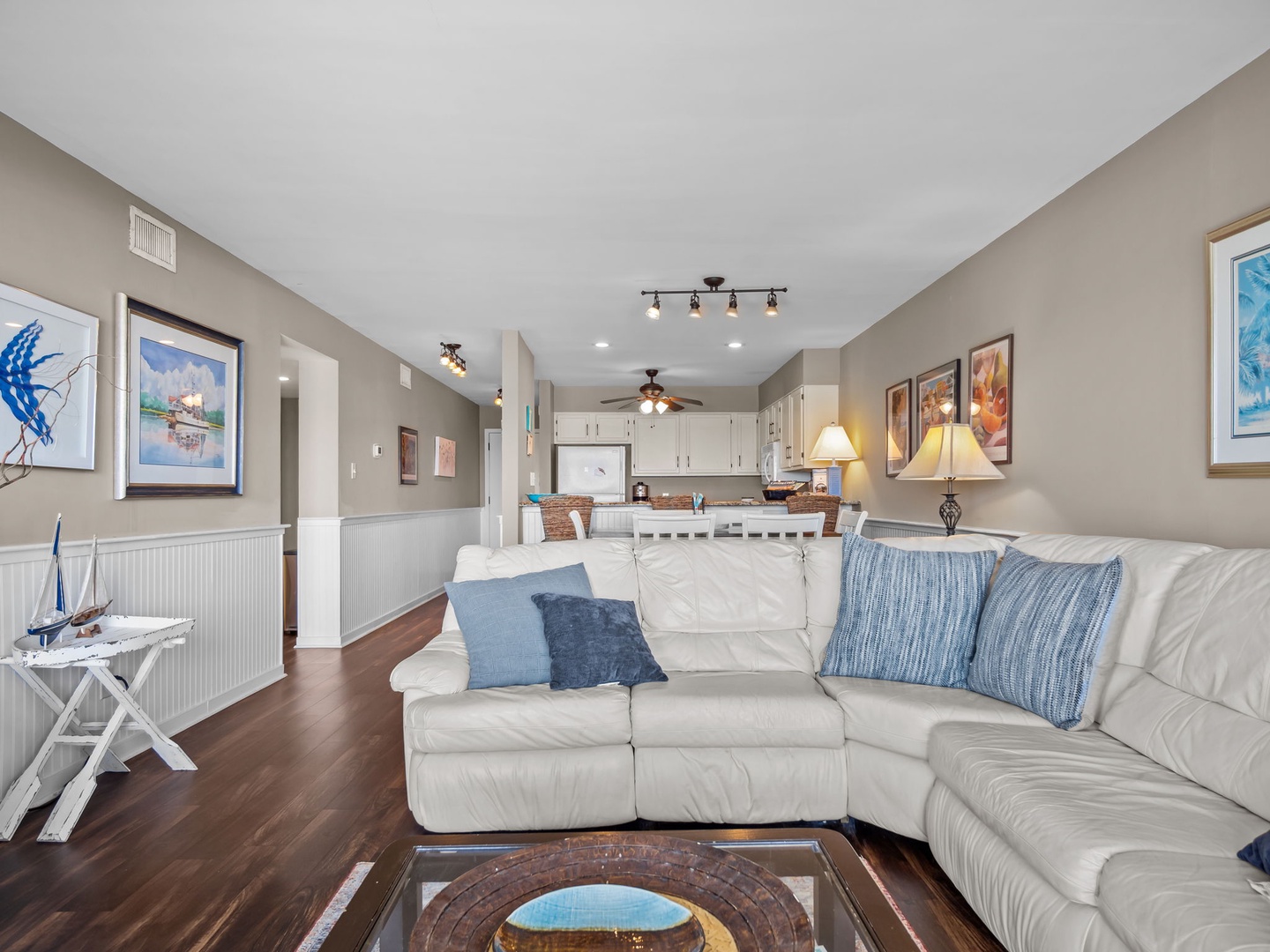 Sink into plush leather seating in your open-concept living space, where coastal artwork and warm lighting create the perfect atmosphere for relaxation.