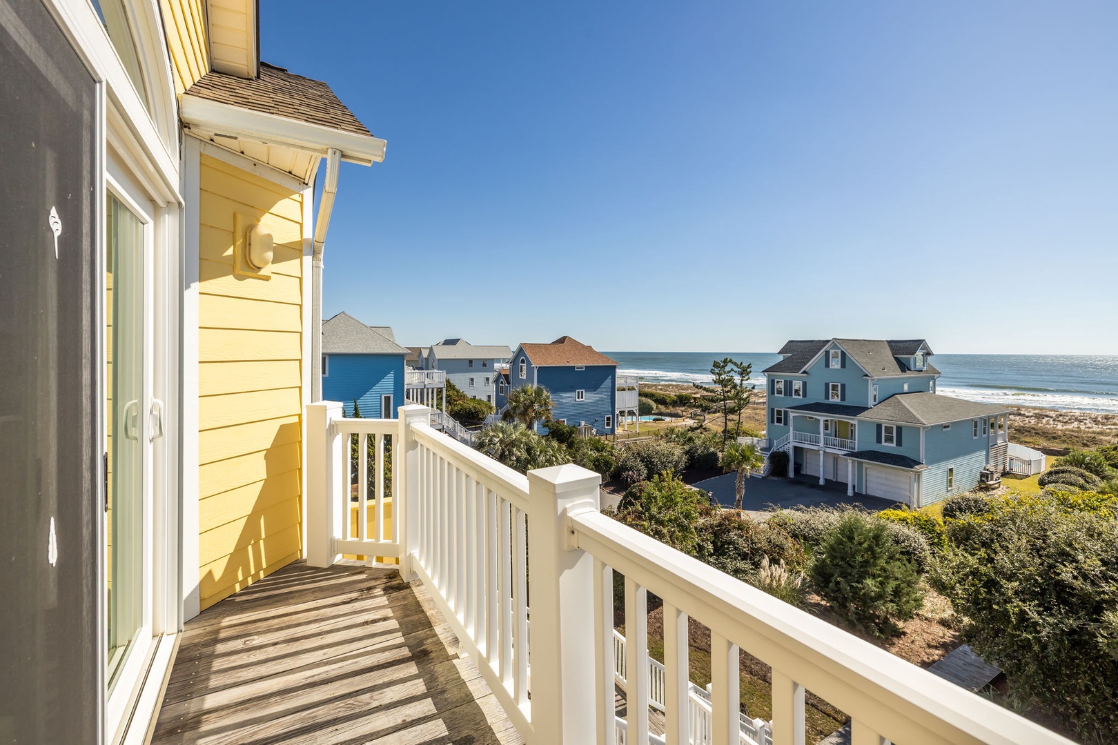 Charming coastal neighborhood with colorful beach houses and ocean views stretching to the horizon.