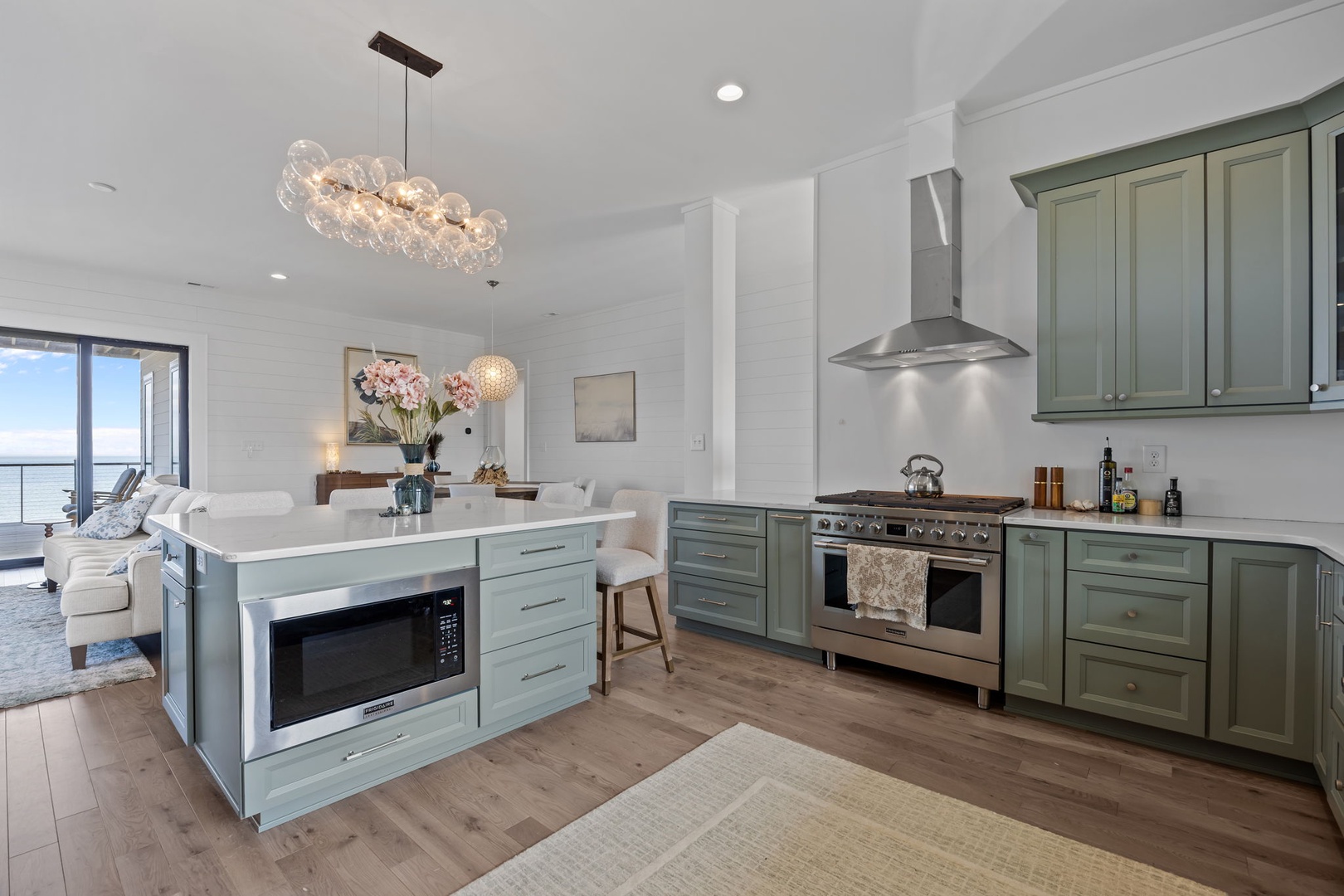 Your gourmet kitchen features premium appliances and elegant sage cabinetry, perfect for creating memorable meals in this light-filled space.