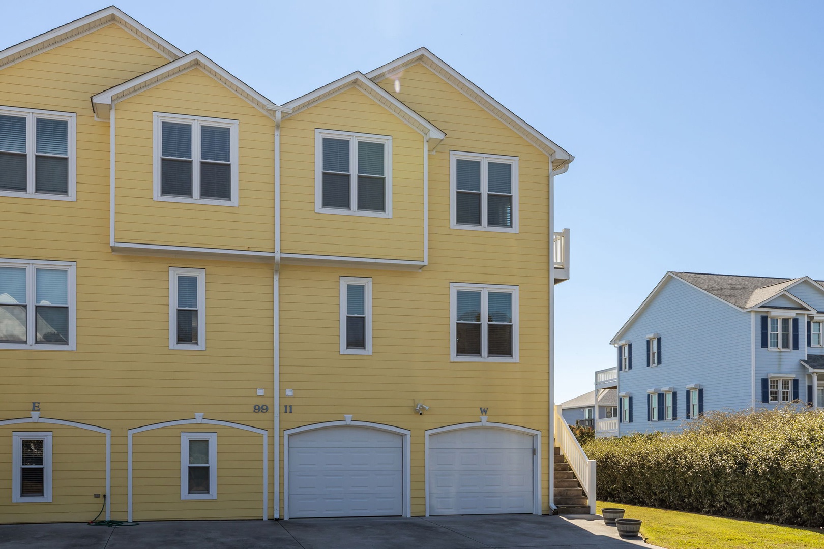 Charming coastal property featuring bright yellow siding and convenient garage access in a peaceful residential setting.