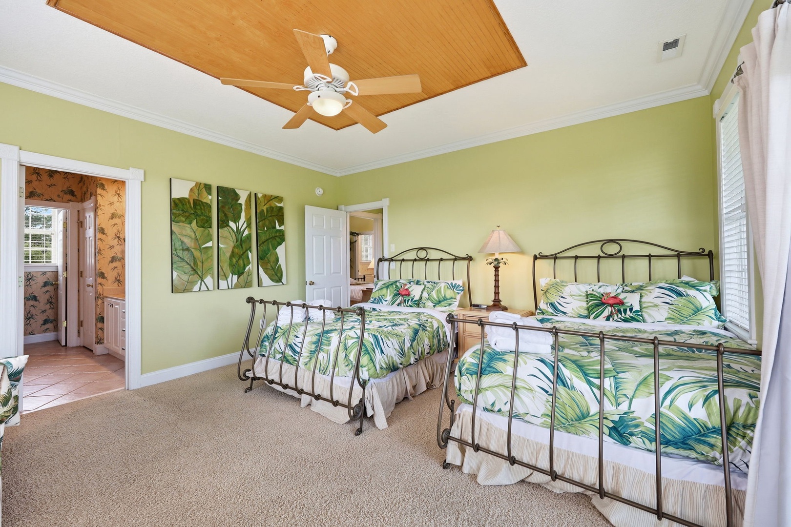 Drift off in your tropical-themed bedroom with two plush beds, botanical artwork, and a warm wooden ceiling fan keeping you comfortable all night.