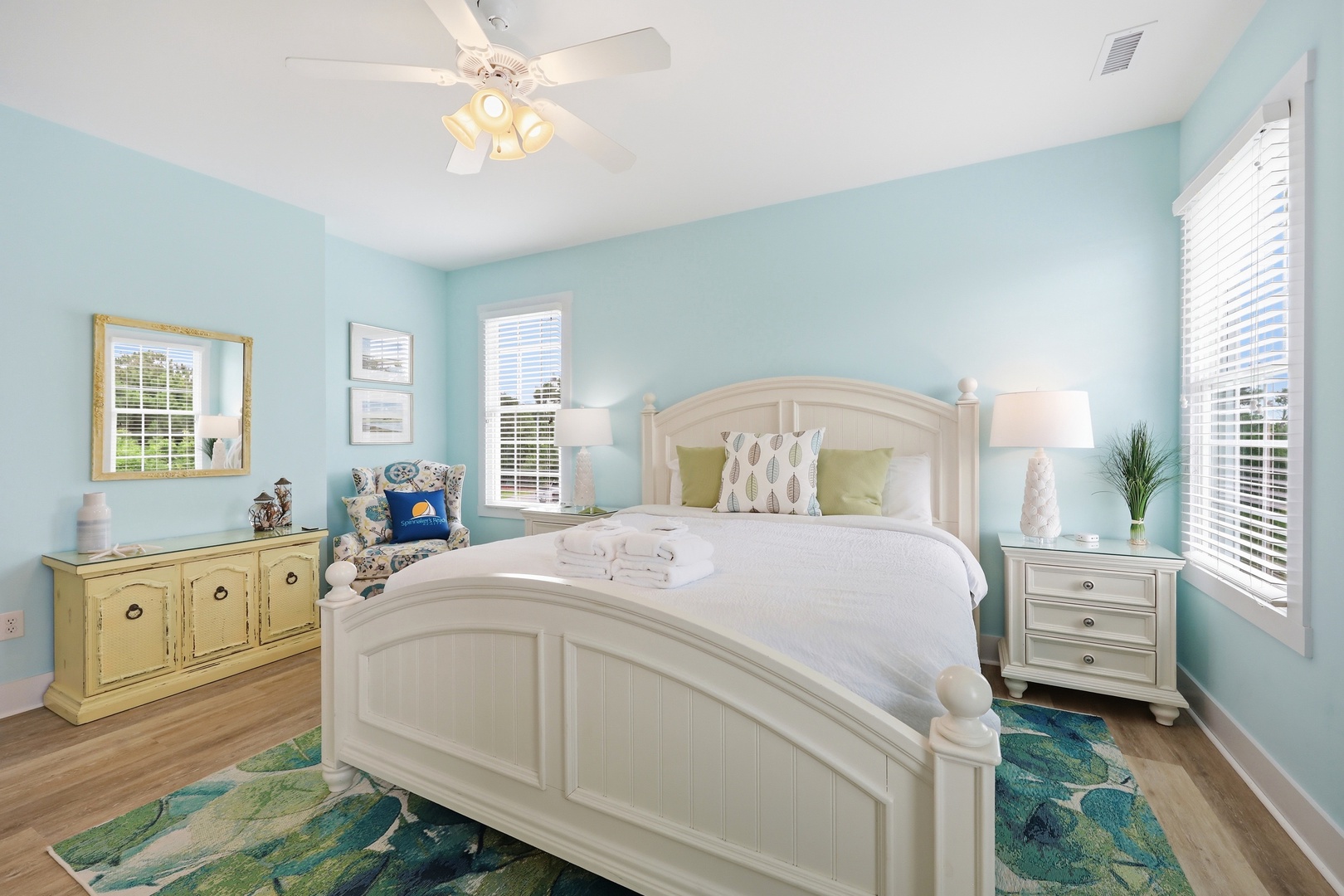 Drift off to sleep in this peaceful coastal bedroom, where soft aqua walls and crisp white linens invite you to unwind. The ceiling fan keeps things cool and comfortable for your stay.