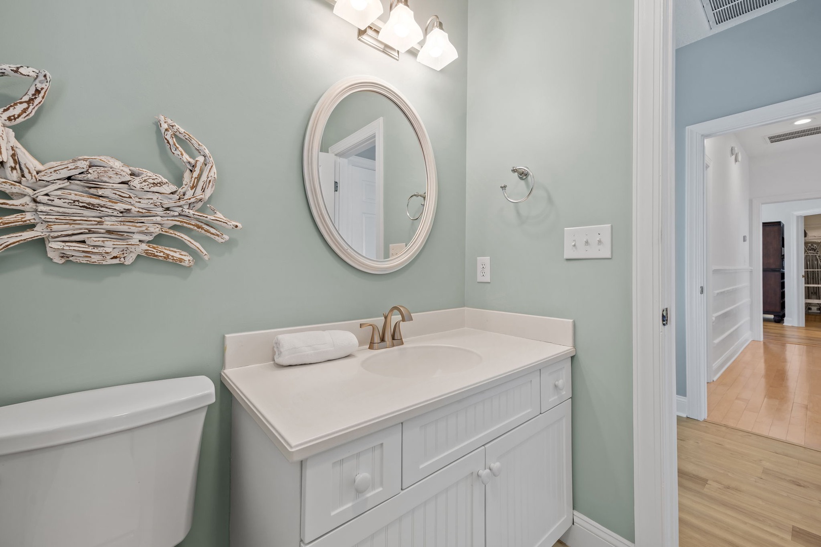 Freshen up in your coastal-inspired bathroom with calming sea-green walls, charming crab artwork, and crisp white vanity.