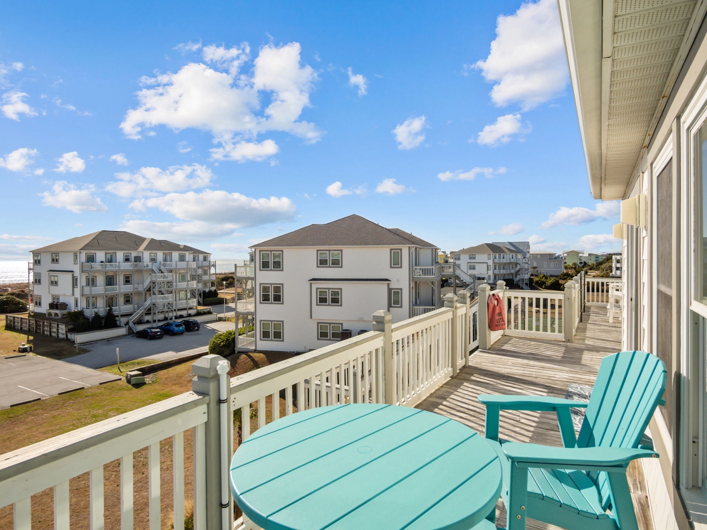 Relax on your private balcony with turquoise furniture, enjoying neighborhood views and fresh ocean air under beautiful blue skies.