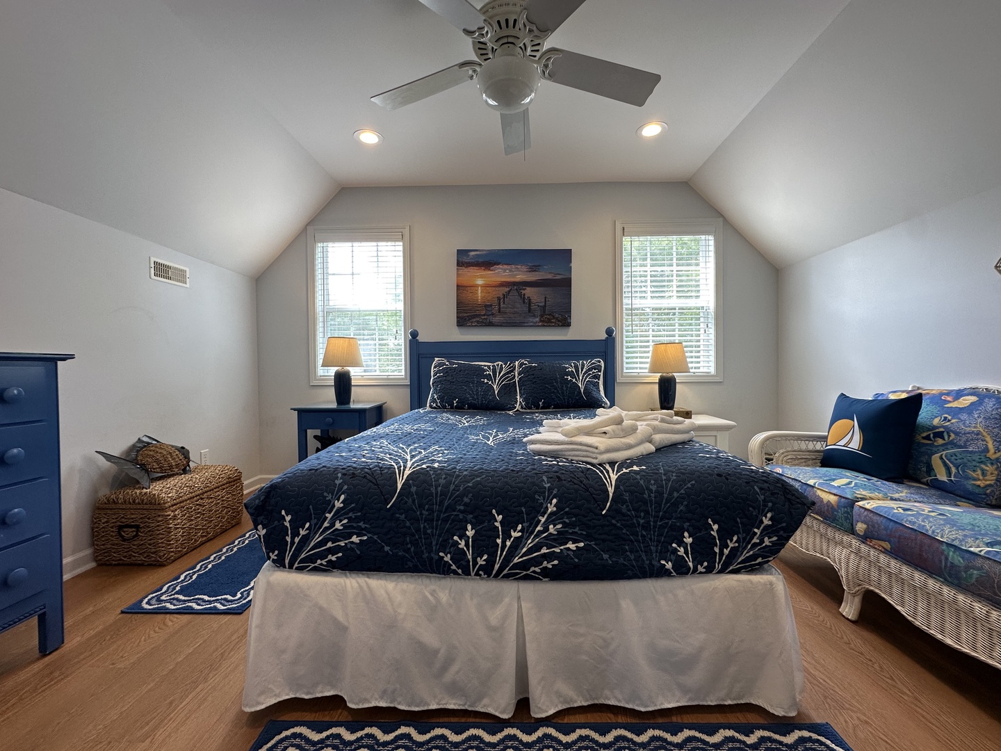 Sink into soft coastal linens and wake to natural light streaming through dual windows. The vaulted ceiling and ceiling fan keep your sanctuary fresh and airy.