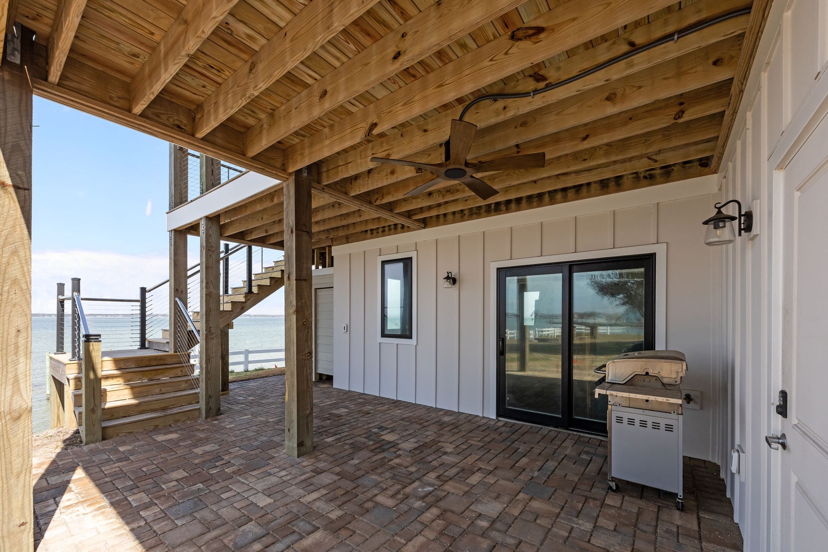 Your private covered deck offers stunning waterfront BBQ moments with rustic wood beams overhead and ocean views stretching endlessly ahead.