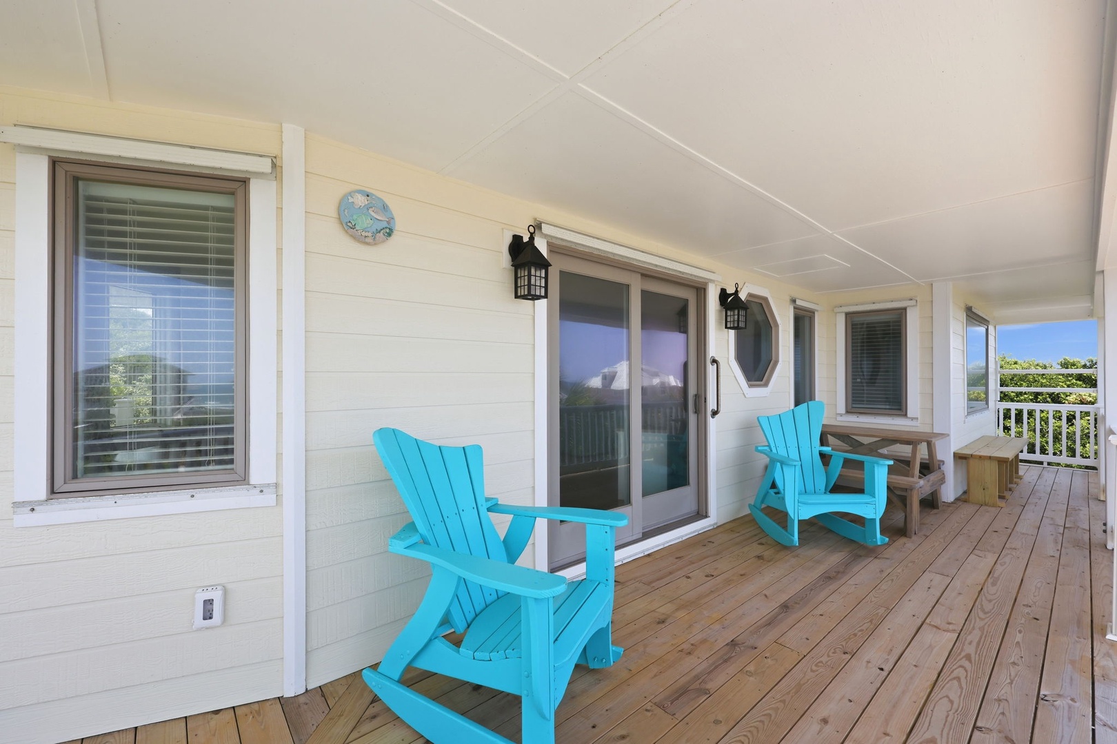 Imagine yourself unwinding here—bright turquoise chairs invite you to settle in, ocean breeze in hand, as natural light spills across the welcoming deck where relaxation meets coastal charm.
