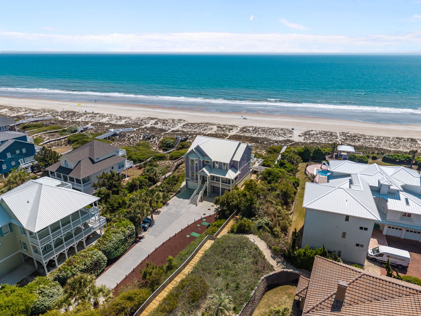 Stunning beachfront property nestled among coastal homes, offering direct access to pristine sandy shores and endless ocean views.