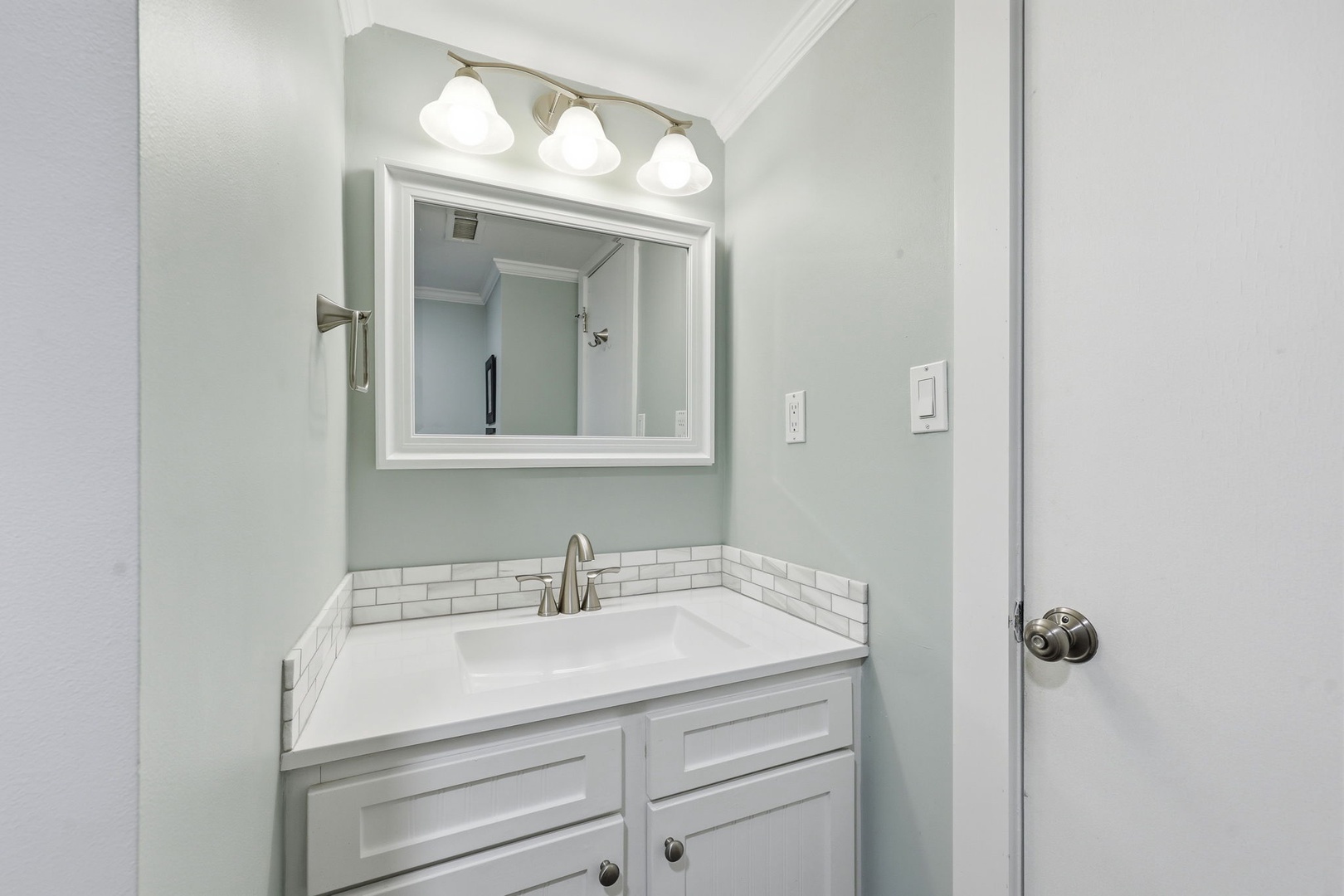 Your bright, beautifully updated bathroom features a crisp white vanity, subway tile accents, and soothing mint walls that create a fresh, spa-like retreat for your morning routine.