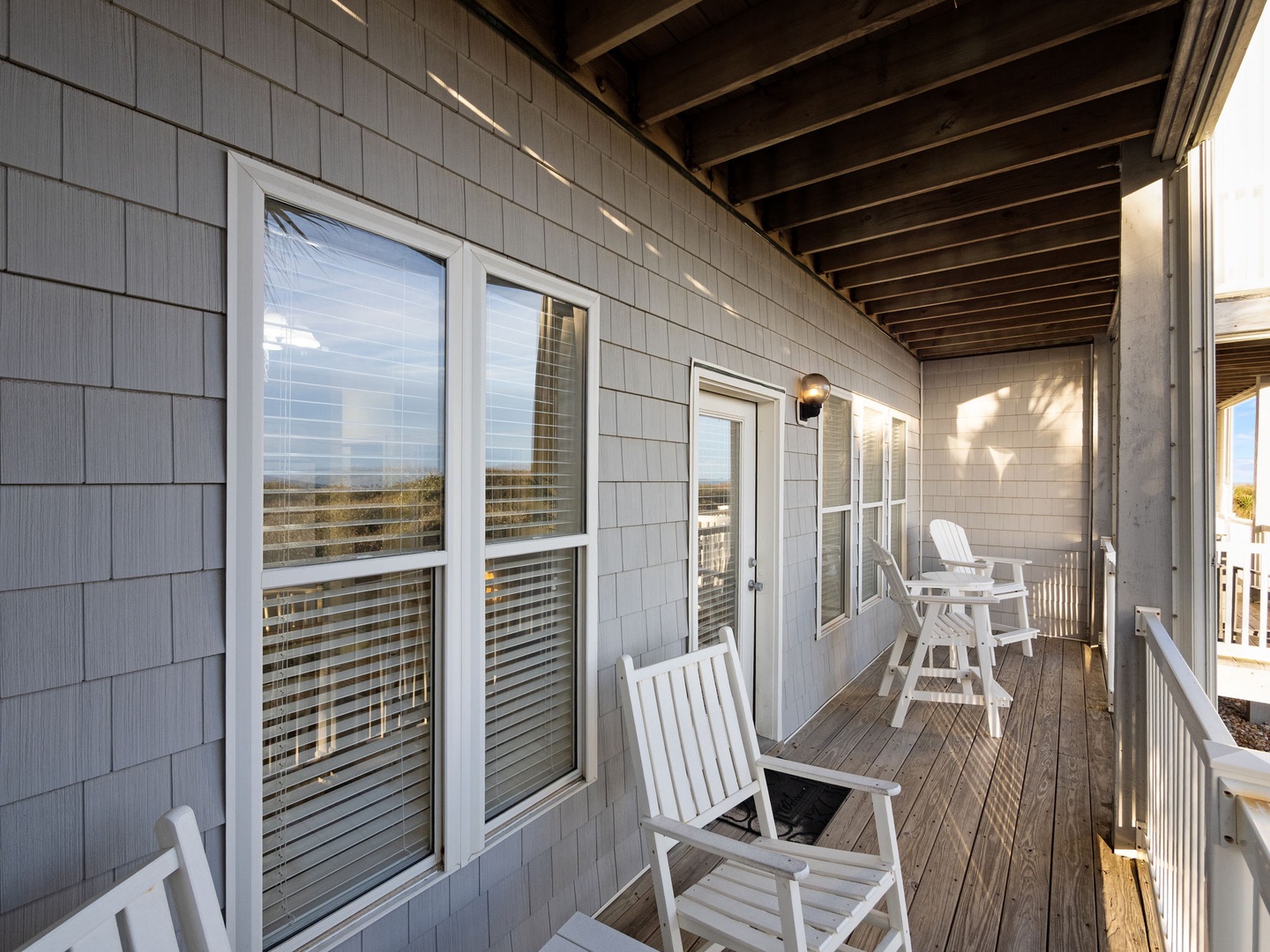 Step onto your private covered balcony where white rocking chairs invite you to unwind while gentle breezes carry ocean whispers through the afternoon light.