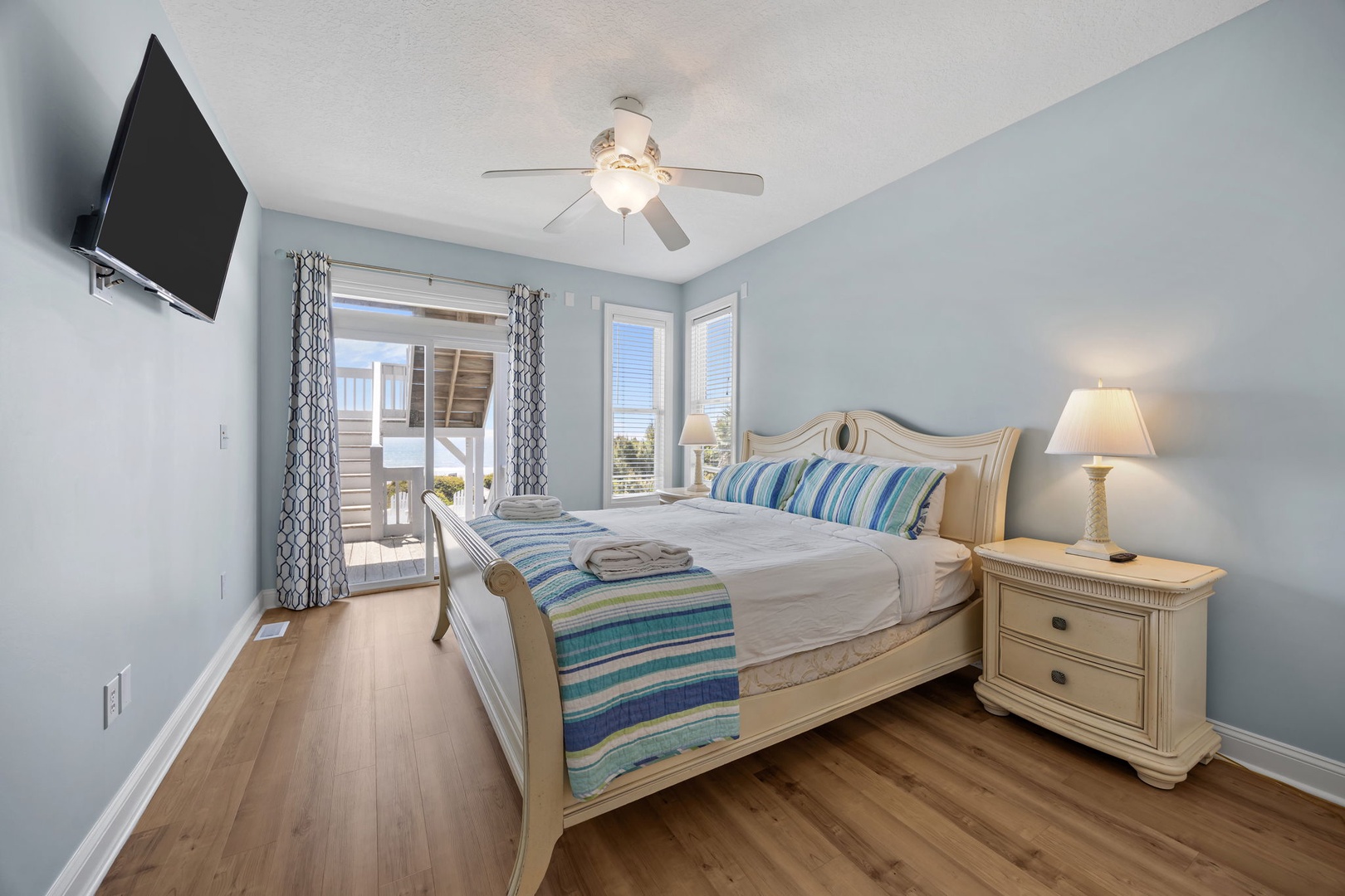 Drift off in your serene coastal bedroom with calming blue walls, crisp linens, and ocean breezes flowing through your private balcony.