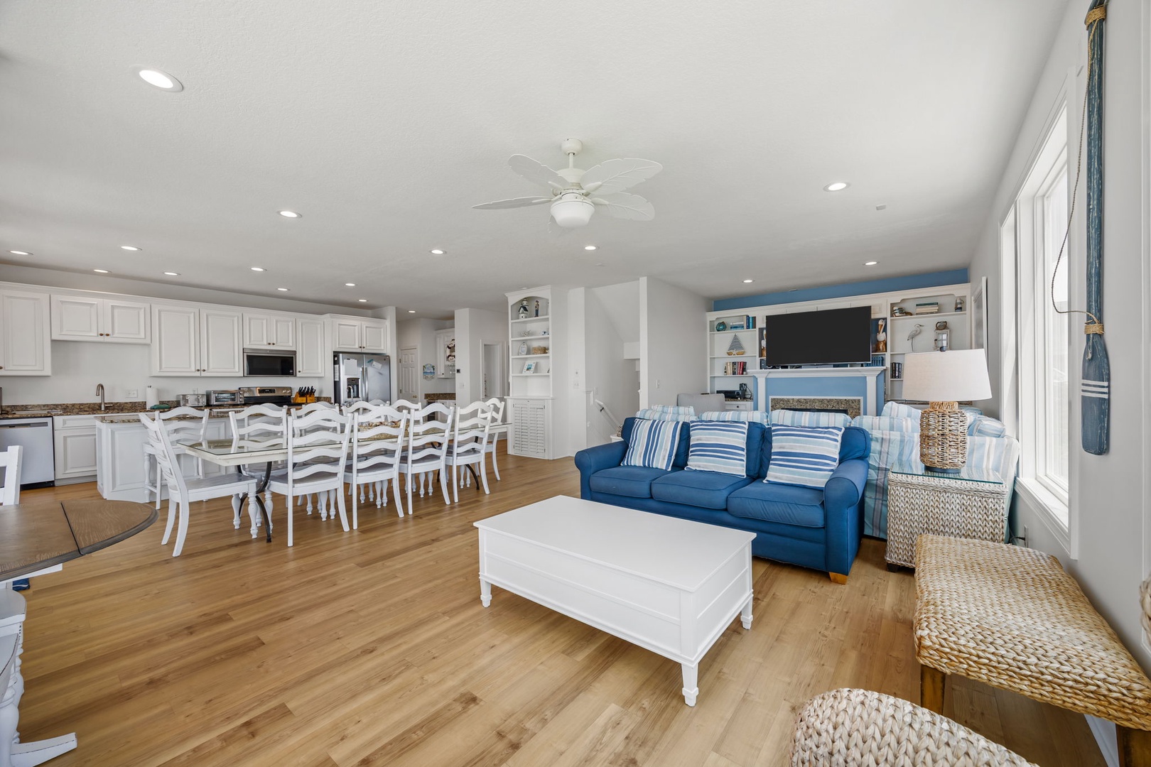 You'll love this bright open-concept space where gleaming white kitchen flows into comfortable living room with coastal blue sofa and dining for eight.