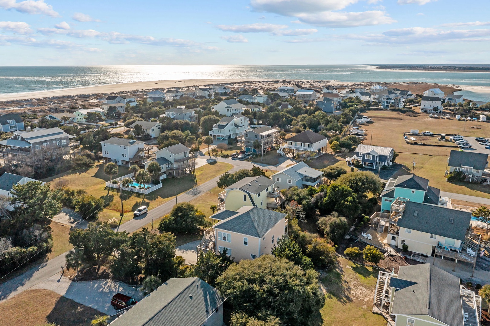 Aerial view of a coastal community featuring beach houses nestled among trees, with pristine sandy beaches and ocean views nearby.