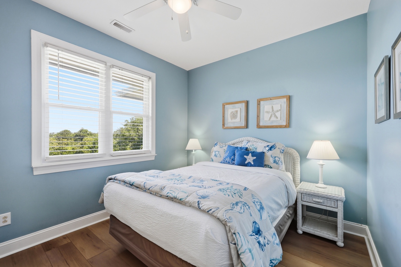 Drift off in this serene coastal bedroom where soft blue walls and ocean-themed touches create your perfect seaside escape. Fresh breezes and natural light complete the tranquil atmosphere.