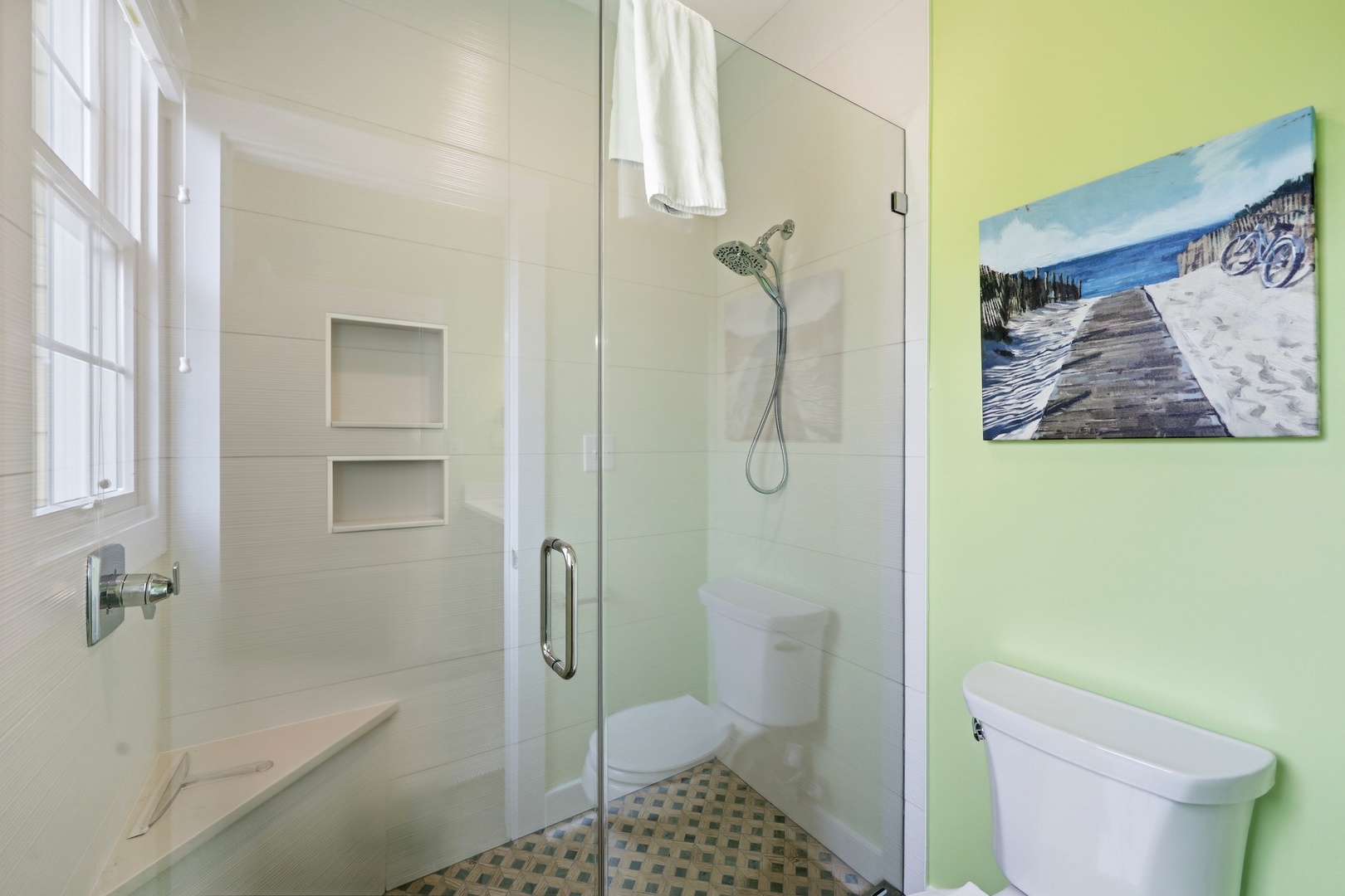 Your bright, clean bathroom features a walk-in shower with crisp white tile, built-in niche storage, and a cheerful coastal-inspired ambiance for refreshing mornings.