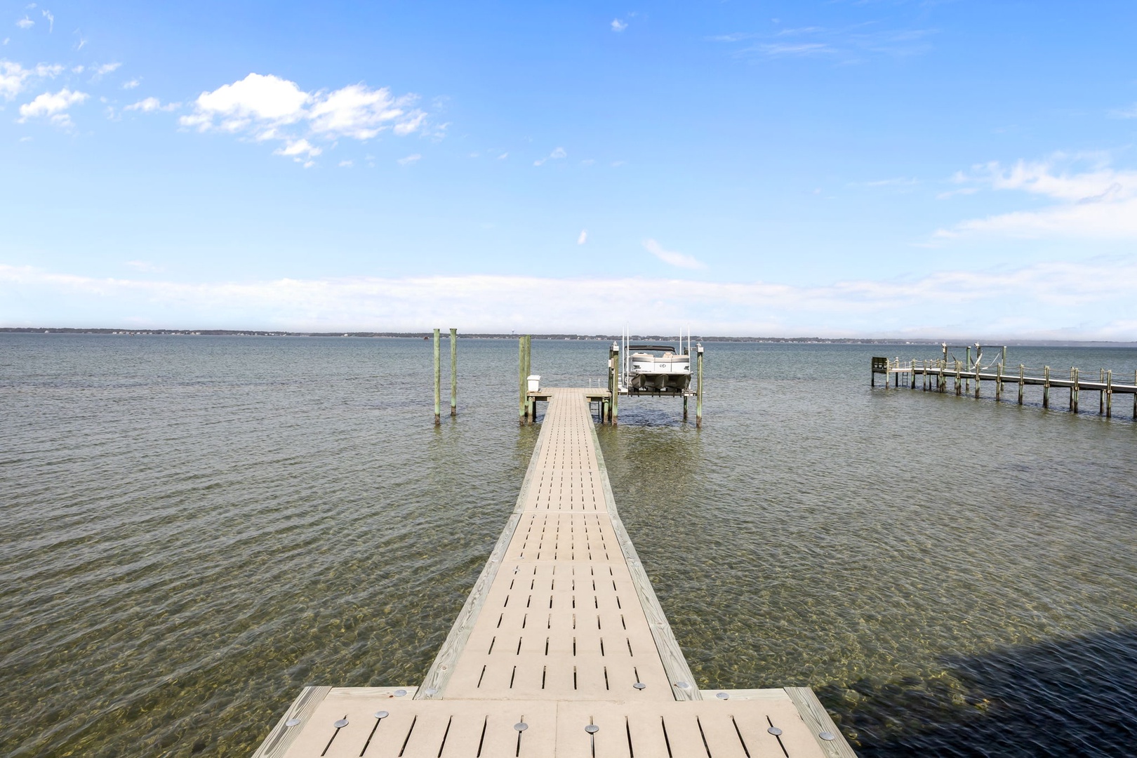 Wooden dock extends into calm waters under blue skies, providing peaceful lakeside access in the surrounding area.