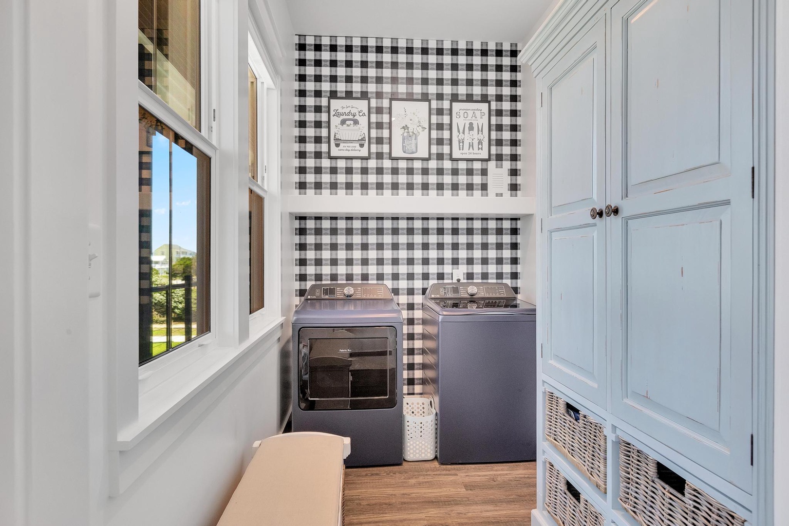 Your dedicated laundry room features a modern washer and dryer set, stylish gingham accent wall, and plenty of natural light to make chores a breeze.
