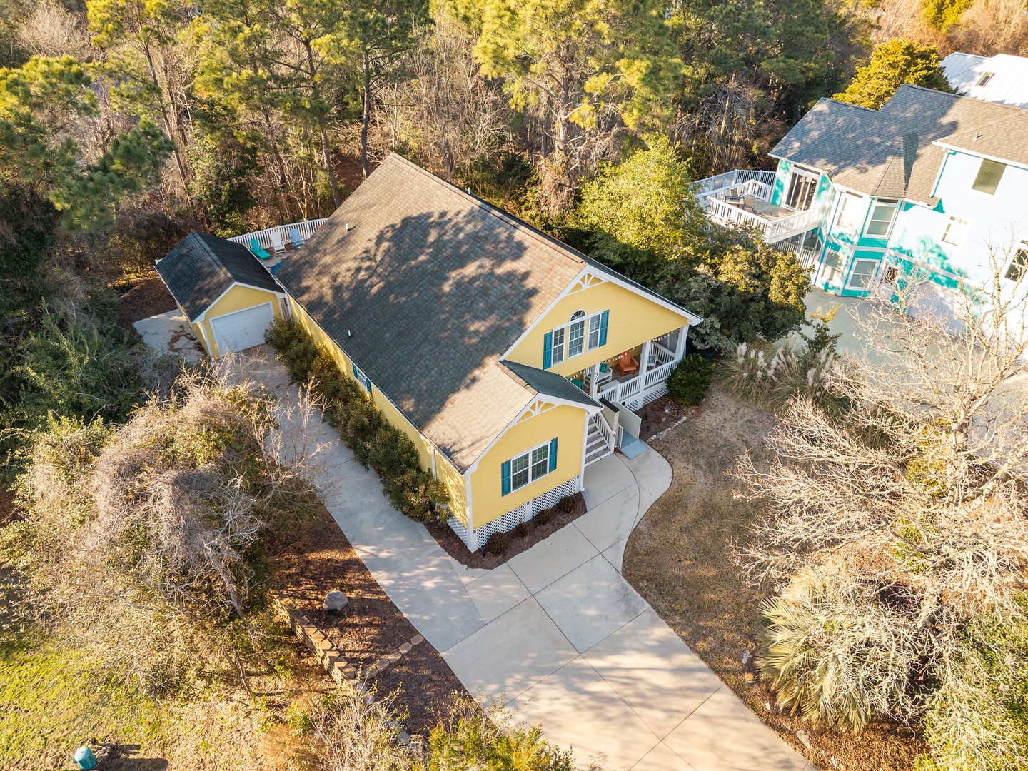 Charming yellow cottage nestled among trees with private driveway and peaceful wooded surroundings.