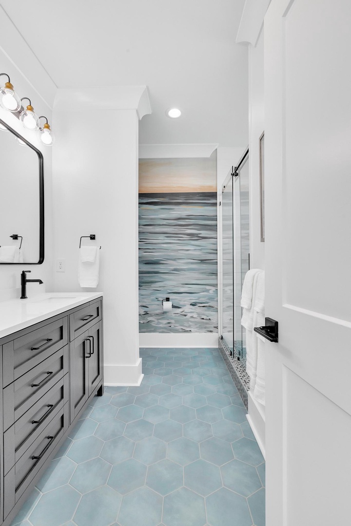 Refresh in this serene coastal-inspired bathroom where soft blues and calming ocean-inspired tiles invite relaxation after a day exploring the area.
