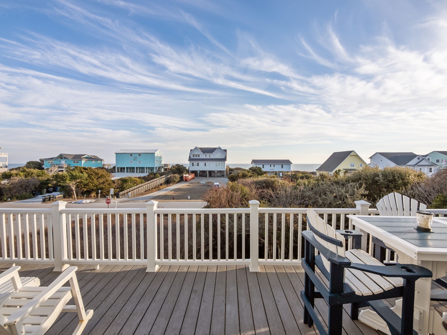 A scenic coastal neighborhood with colorful beach houses stretches beyond this charming outdoor deck area.