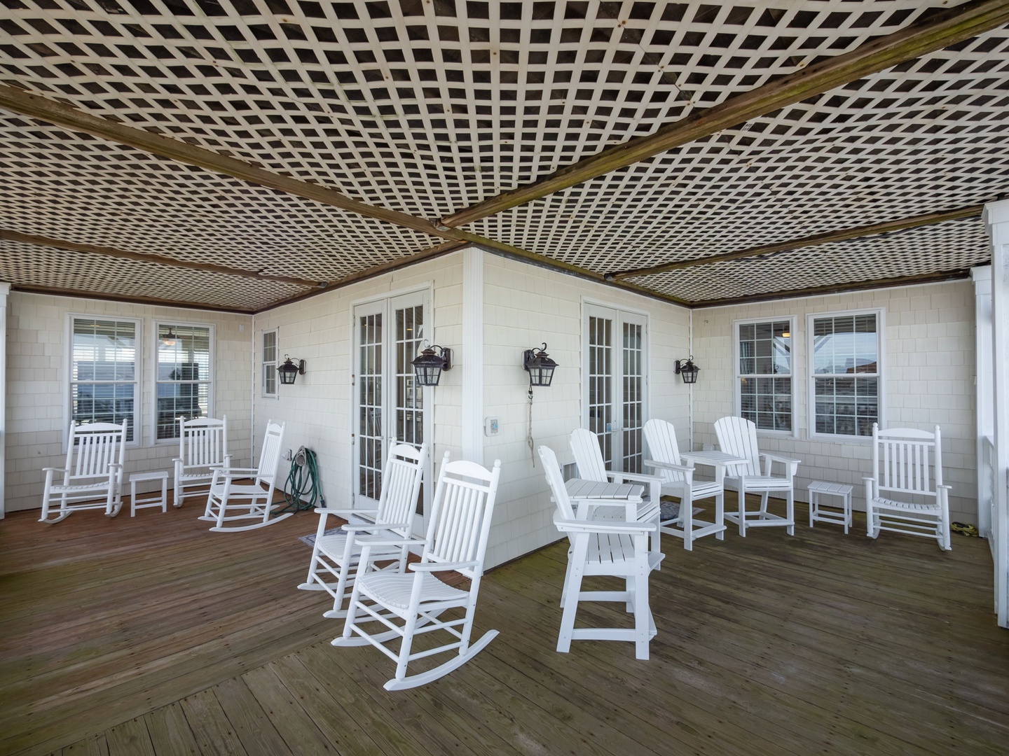 Your spacious covered porch invites you to unwind in classic white rockers, where gentle breezes and peaceful moments await under the charming lattice ceiling.