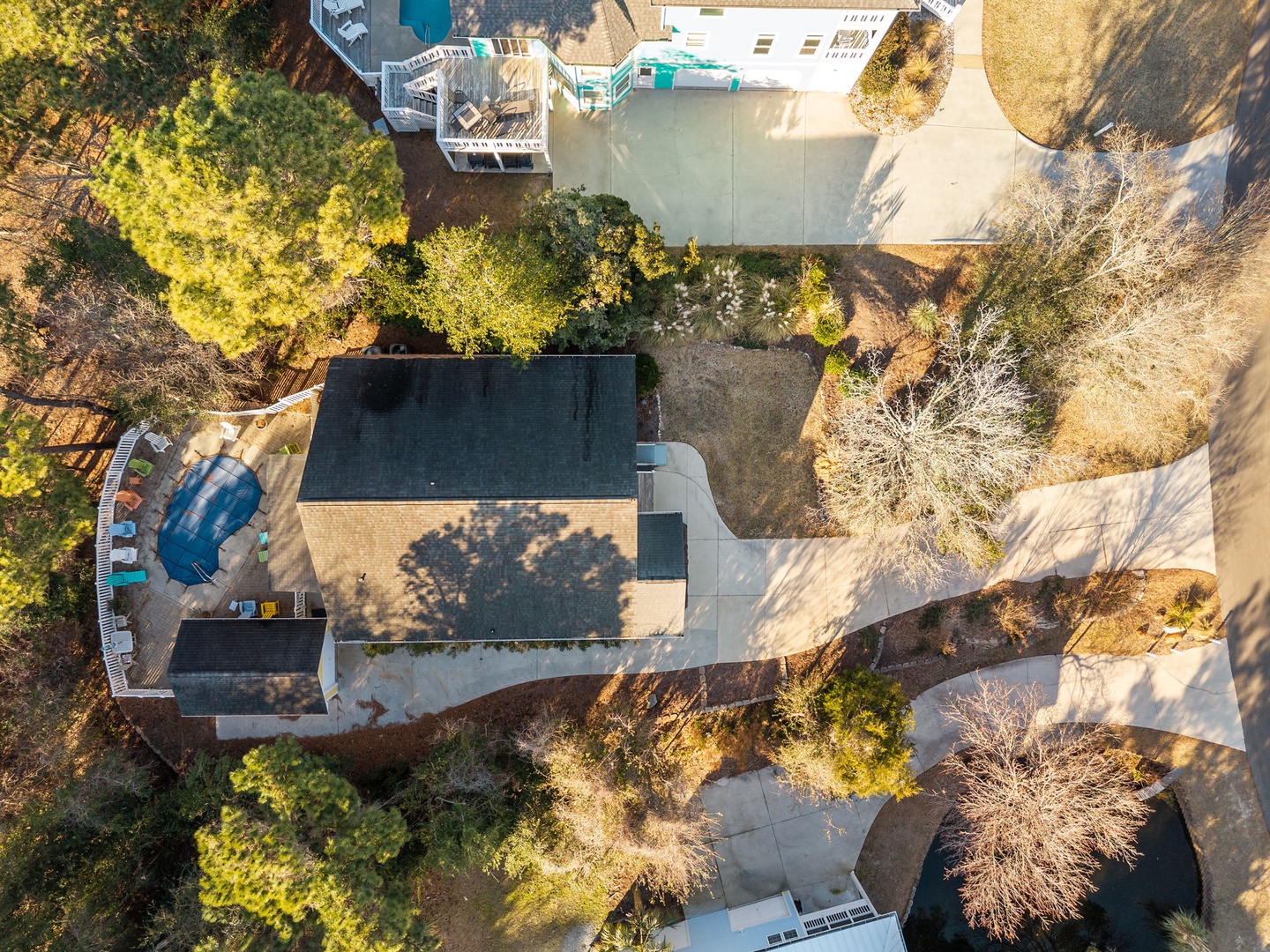 Aerial view of the property showcasing the main building, swimming pool, and beautifully landscaped grounds surrounded by mature trees.