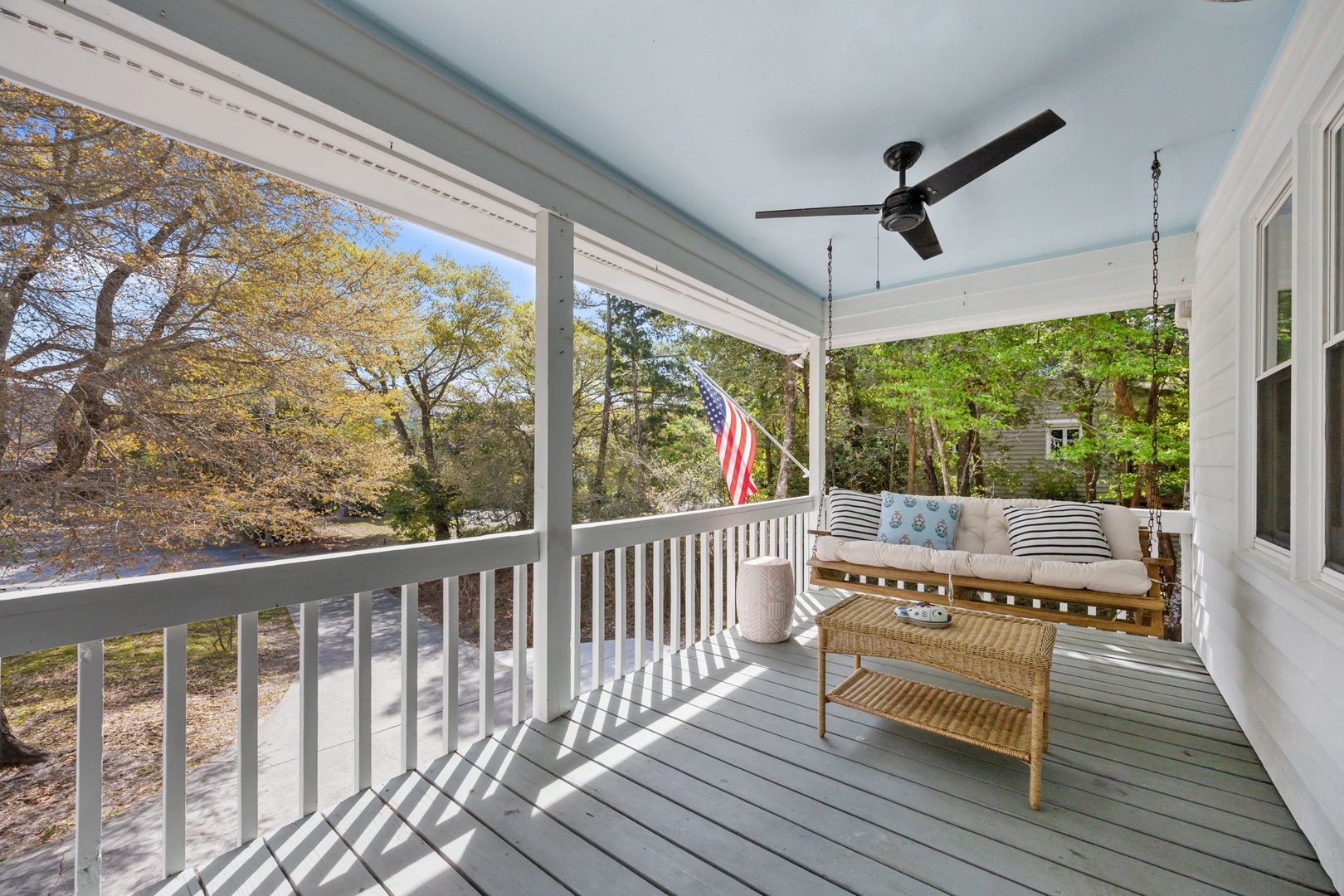Relax on your private covered porch with ceiling fan and cozy seating, overlooking peaceful neighborhood trees.