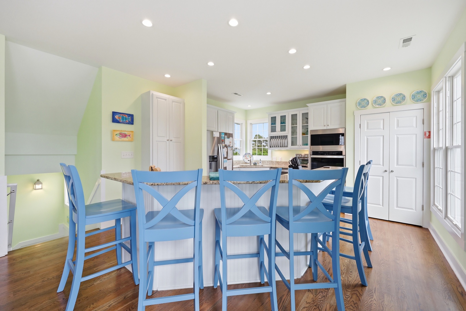Picture yourself preparing meals at this spacious island, with room for everyone to gather on cheerful coastal blue stools. Bright natural light and a breezy palette make every moment feel like a vacation.