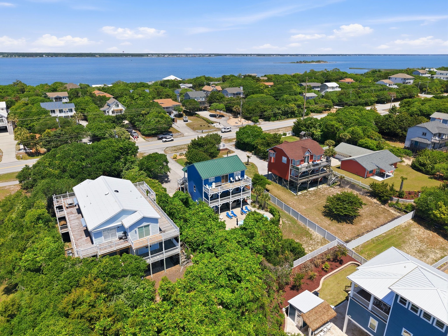 Aerial view of a coastal neighborhood with vacation properties nestled among lush greenery, just moments from pristine bay waters and scenic waterfront access.