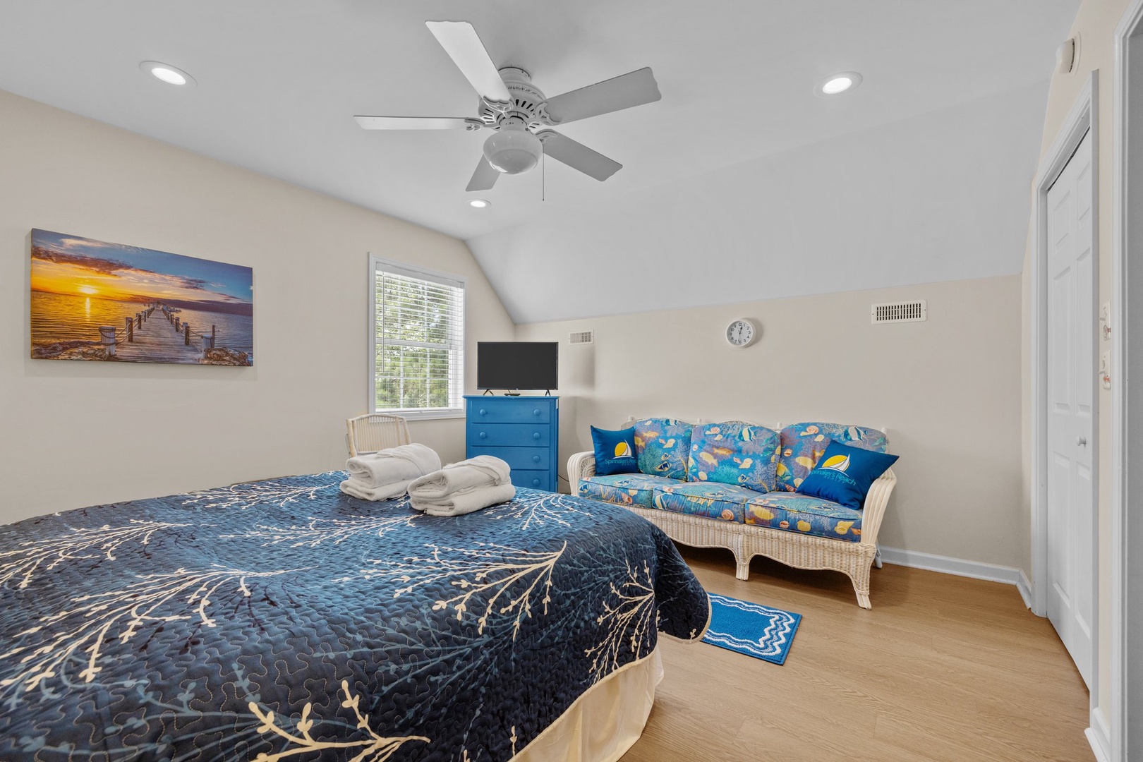 Your peaceful bedroom retreat features a comfy bed, cheerful seating area, and cooling ceiling fan for restful nights.