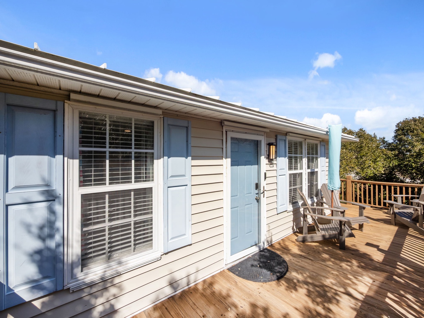 Charming cottage exterior with spacious wooden deck and Adirondack chairs for relaxing in the sunshine.