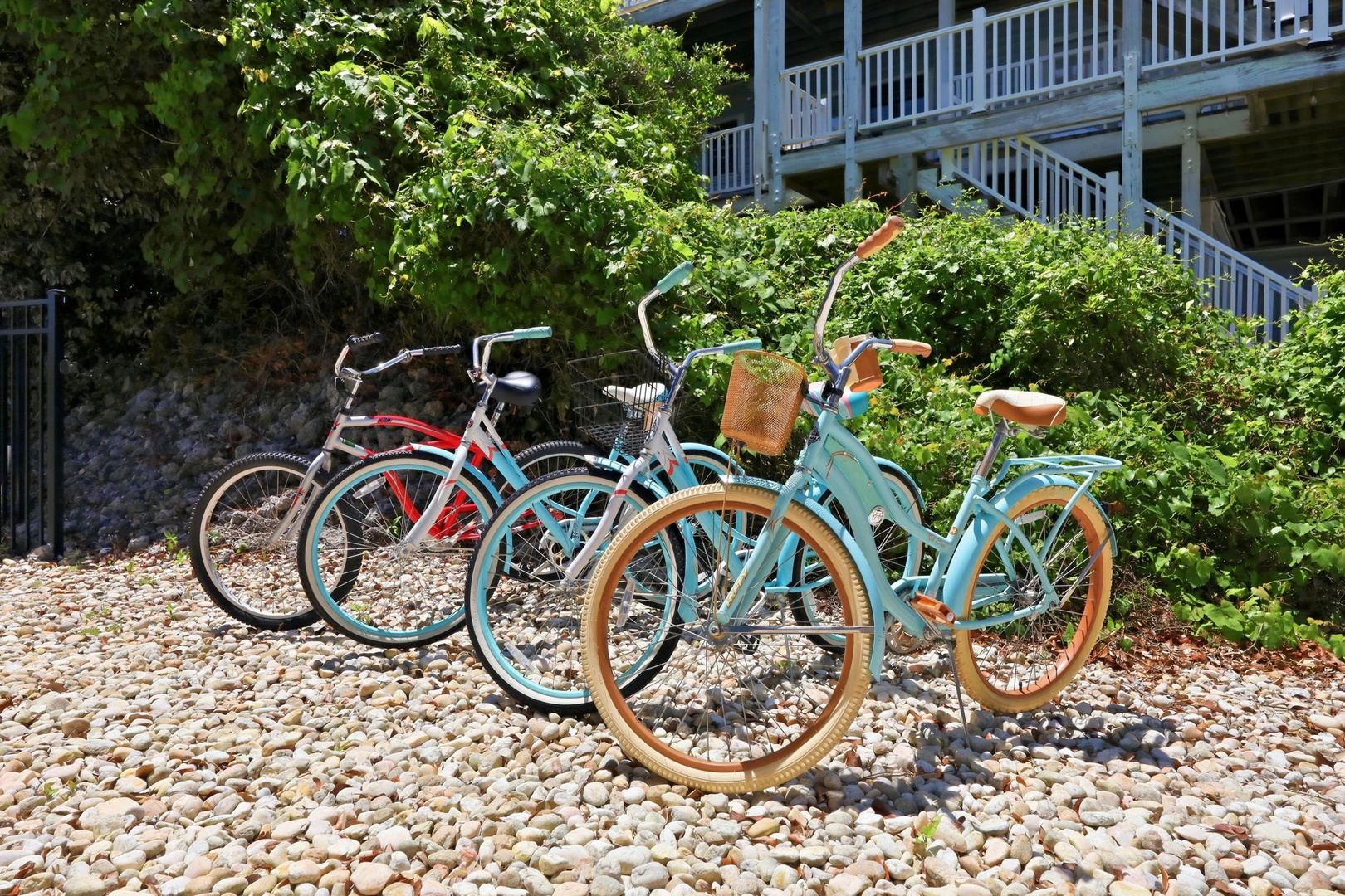 Colorful beach cruisers await on a pebbled path, perfect for exploring scenic coastal trails and nearby attractions during your stay.
