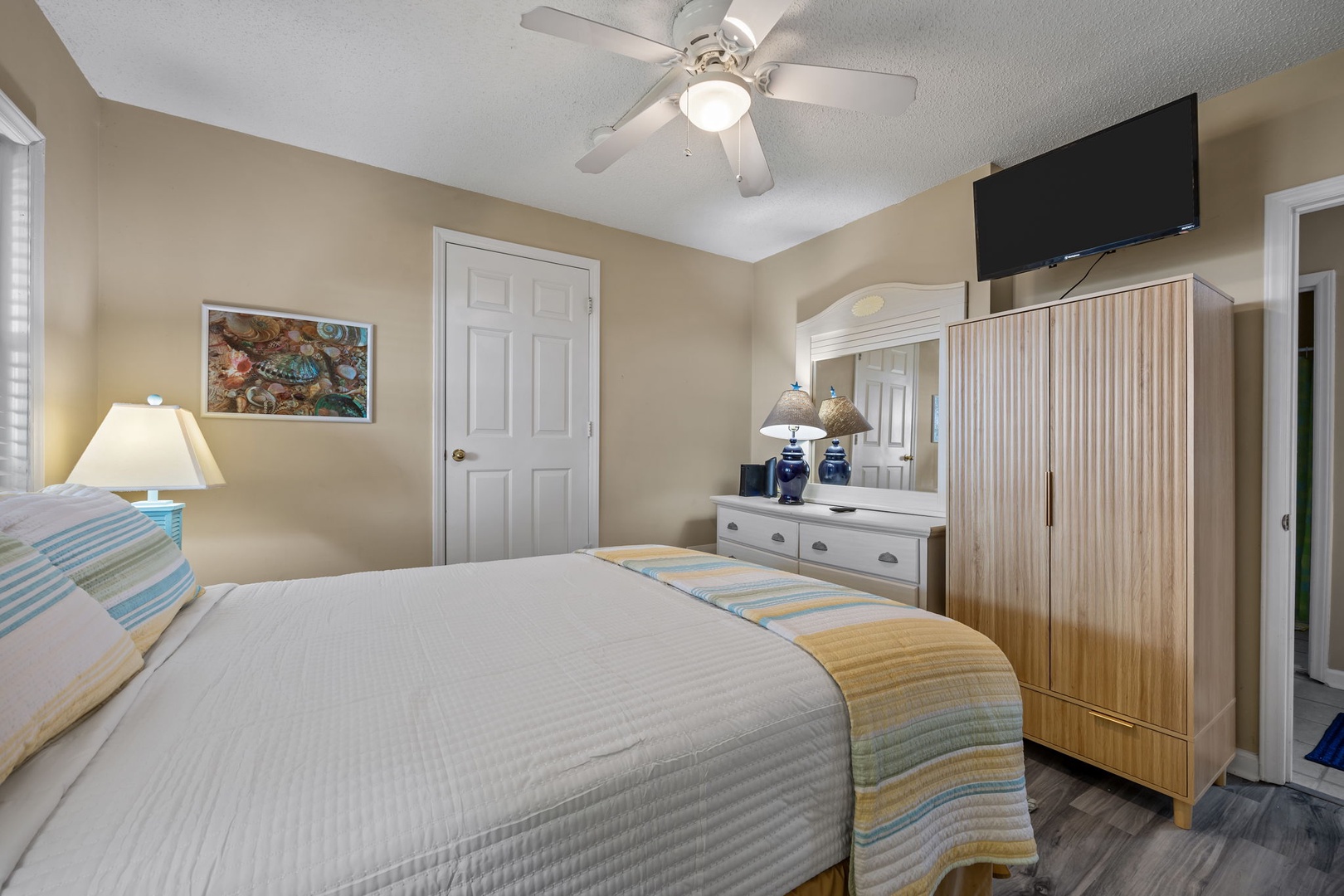 Unwind in your peaceful bedroom with a ceiling fan cooling you while watching TV on the wall-mounted screen.