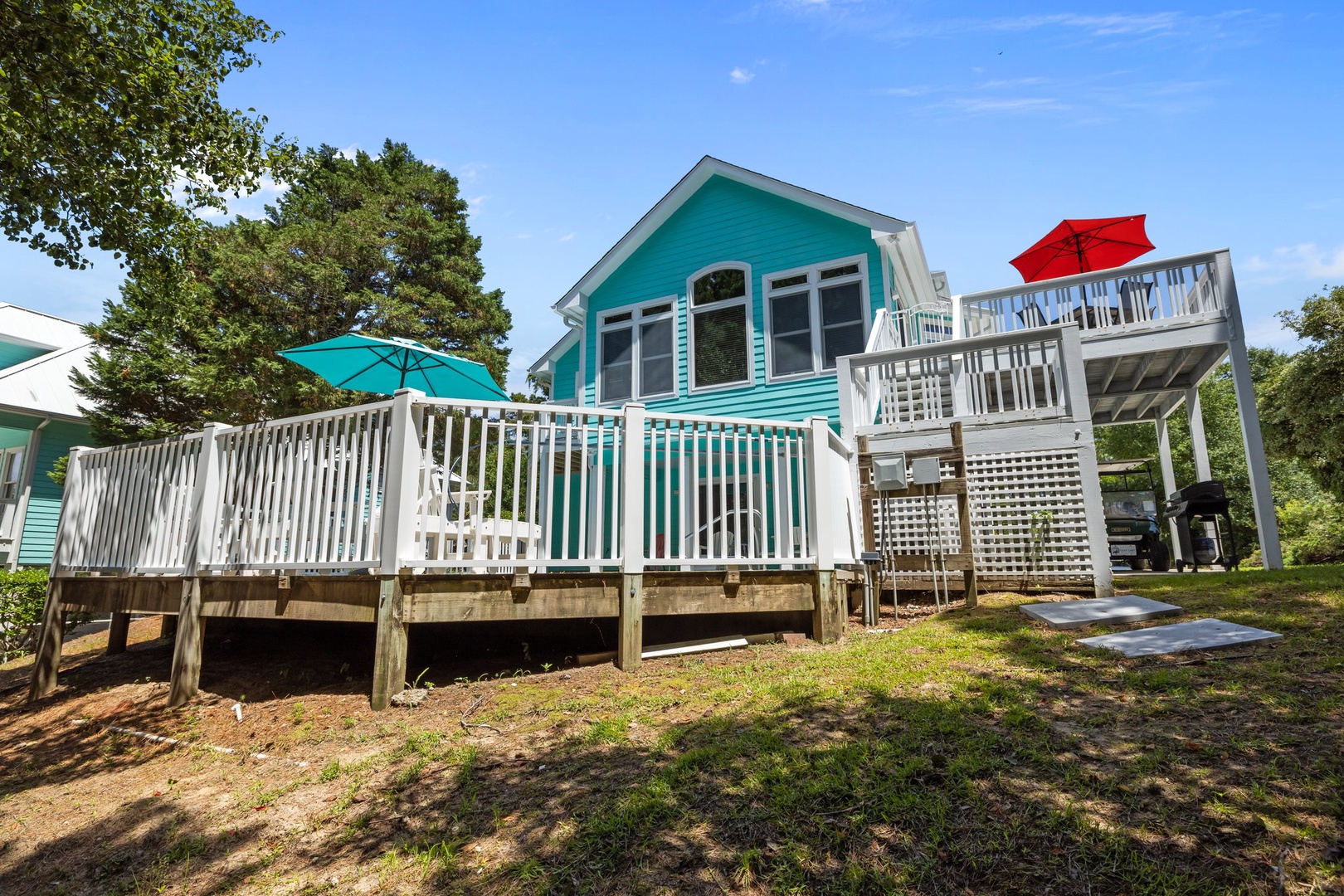 Charming turquoise cottage with spacious decks and outdoor amenities set among mature trees.