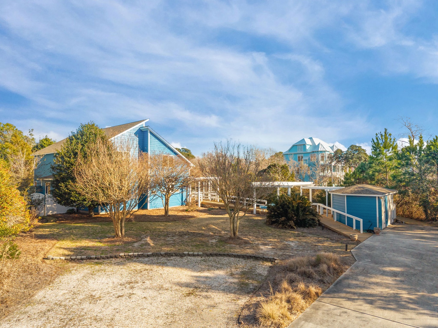 Charming coastal property featuring distinctive blue architecture nestled among mature trees and landscaped grounds with convenient parking access.