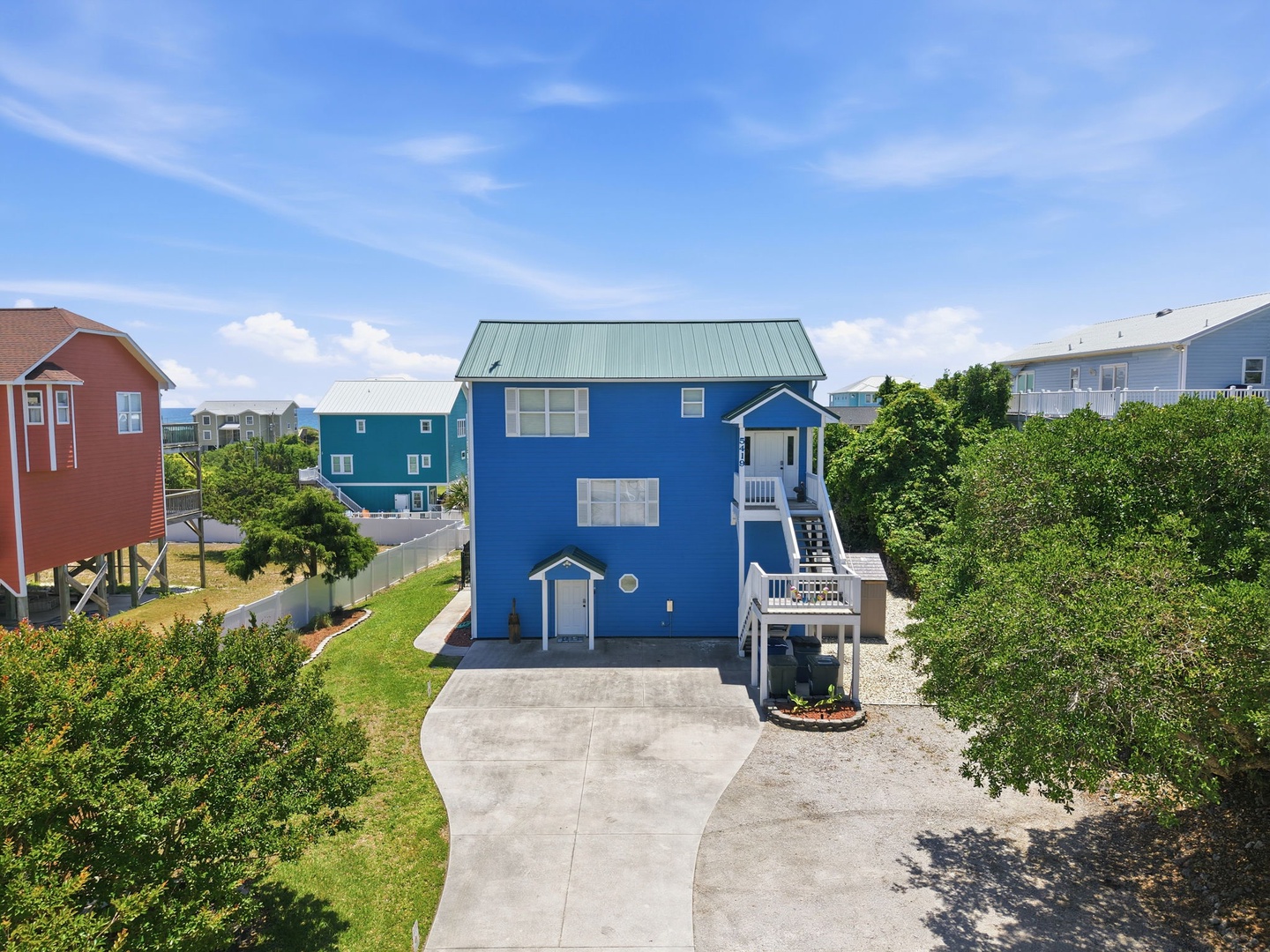 A bright blue coastal home nestled in a quiet residential area, offering easy beach access and a welcoming neighborhood atmosphere.