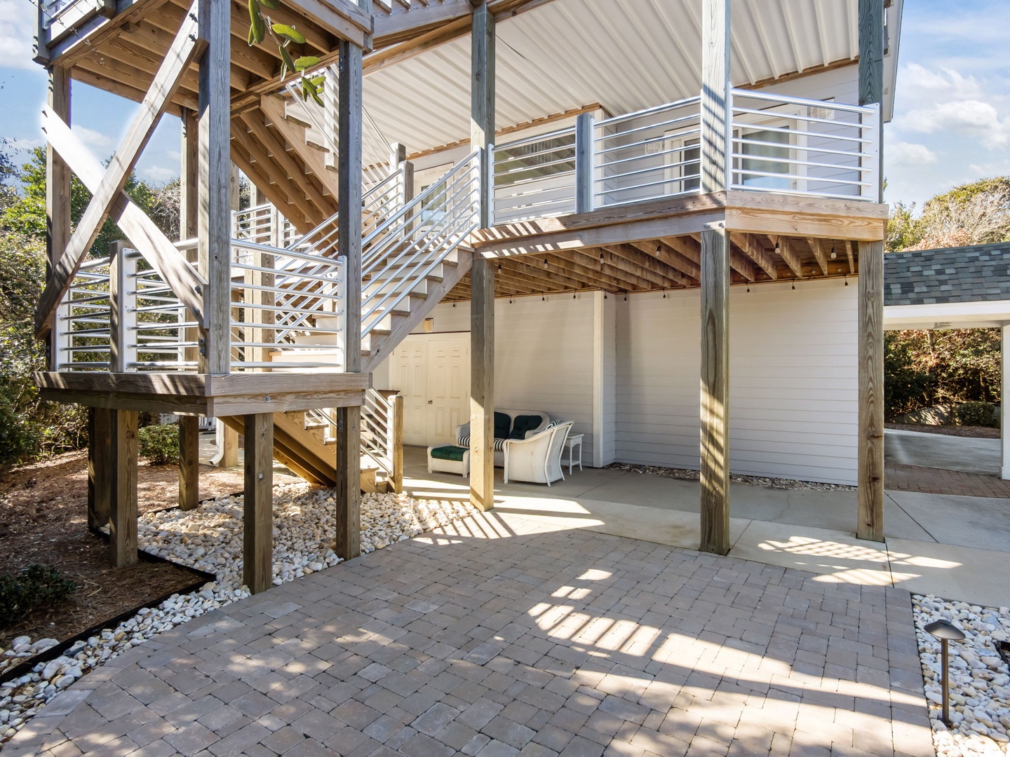 Your private patio features elegant stone pavers beneath a multi-level deck structure, creating perfect spaces for outdoor dining and relaxation.