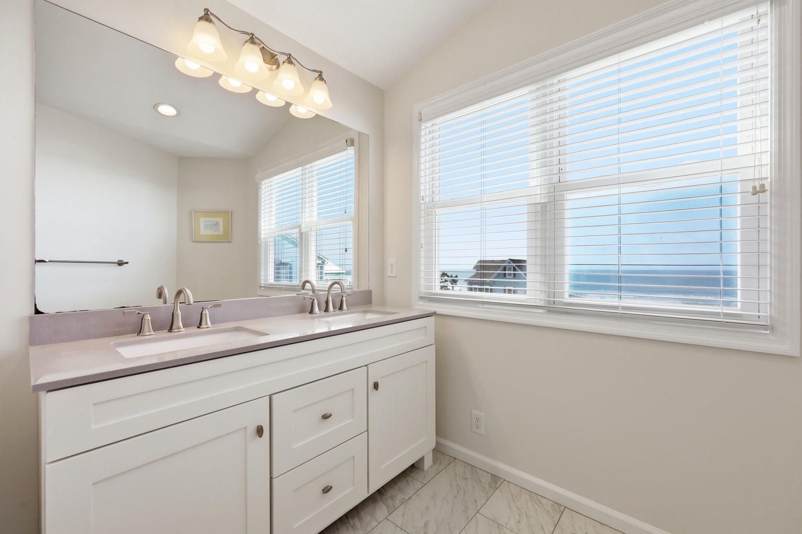 Freshen up in your bright coastal bathroom with dual sinks, stylish fixtures, and serene sea views right from your window.
