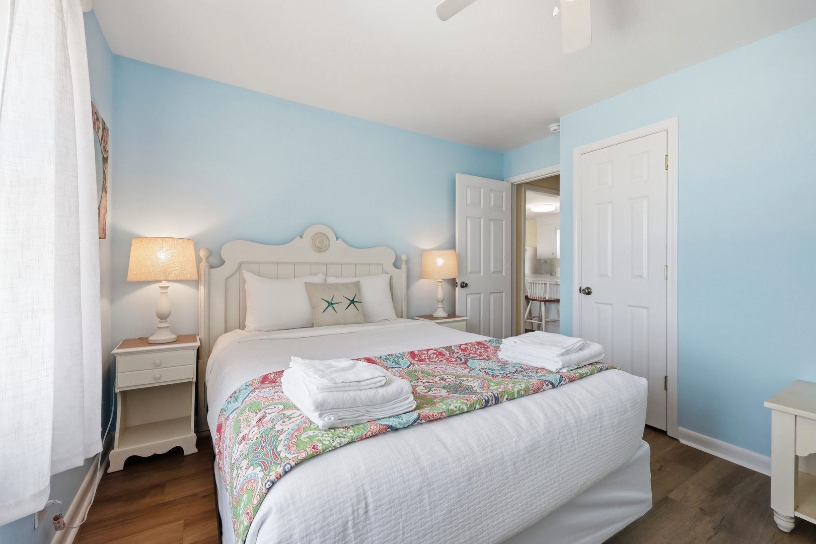 Step into your peaceful coastal retreat with soft blue walls, starfish accents, and crisp linens inviting you to unwind after a day at the beach.