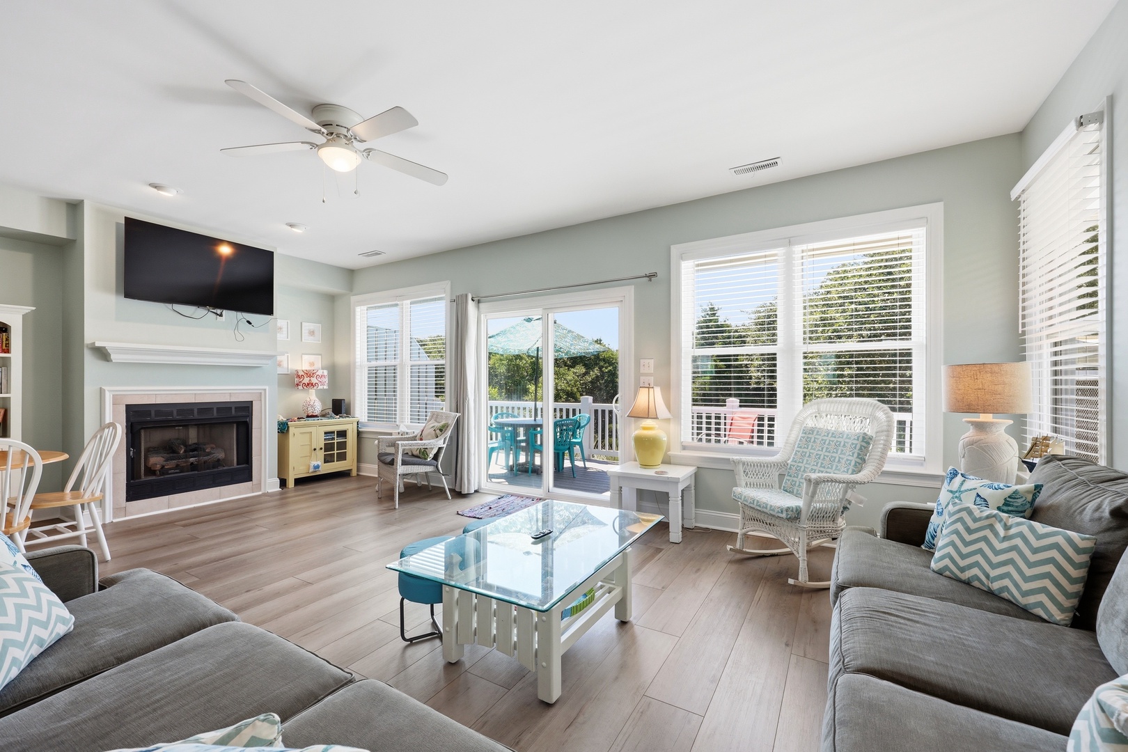 Relax in your bright, breezy living room with coastal decor, a cozy fireplace, and balcony doors opening to fresh air and views.