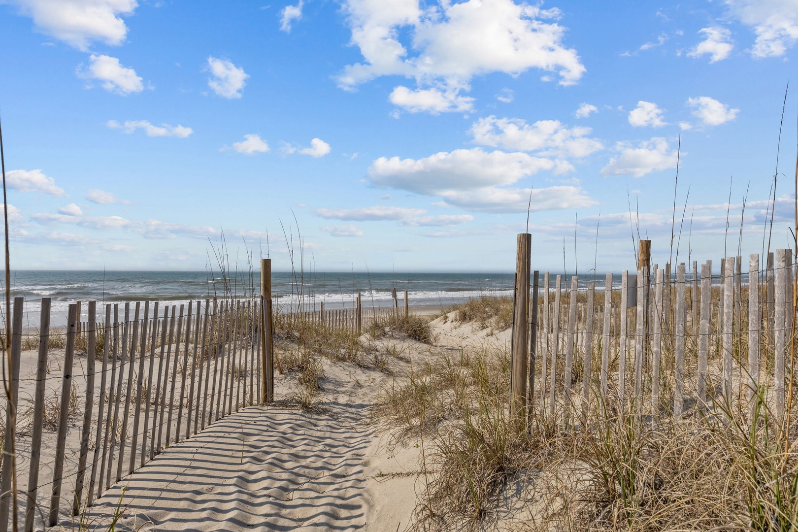 Pristine beach access with dunes and wooden walkway leading to the ocean.