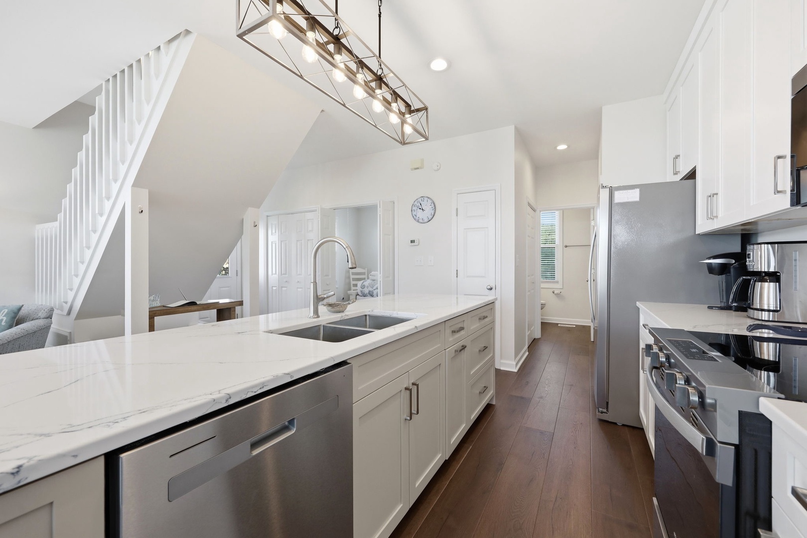 Your fully equipped kitchen features sleek white cabinetry, modern stainless appliances, and a spacious island with a farmhouse sink—perfect for preparing meals together or enjoying morning coffee.