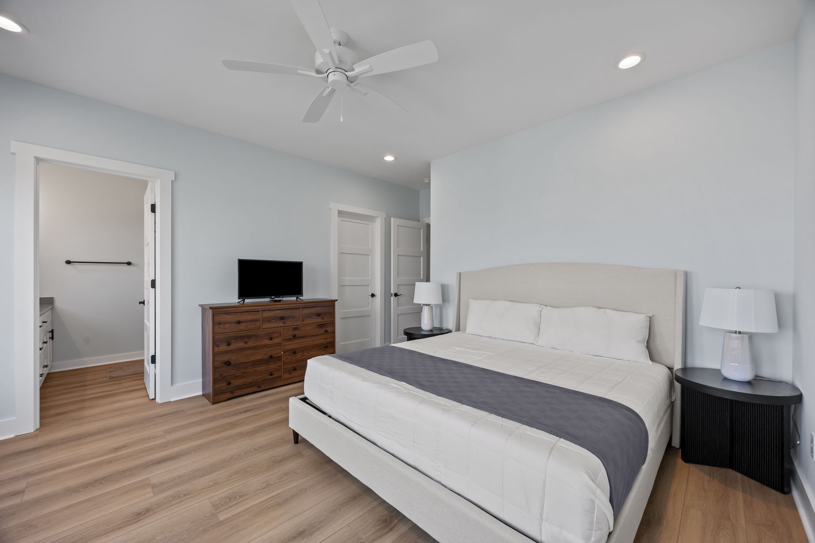 Unwind in this serene bedroom with plush bedding, modern amenities, and gentle ceiling fan for your perfect night's rest.