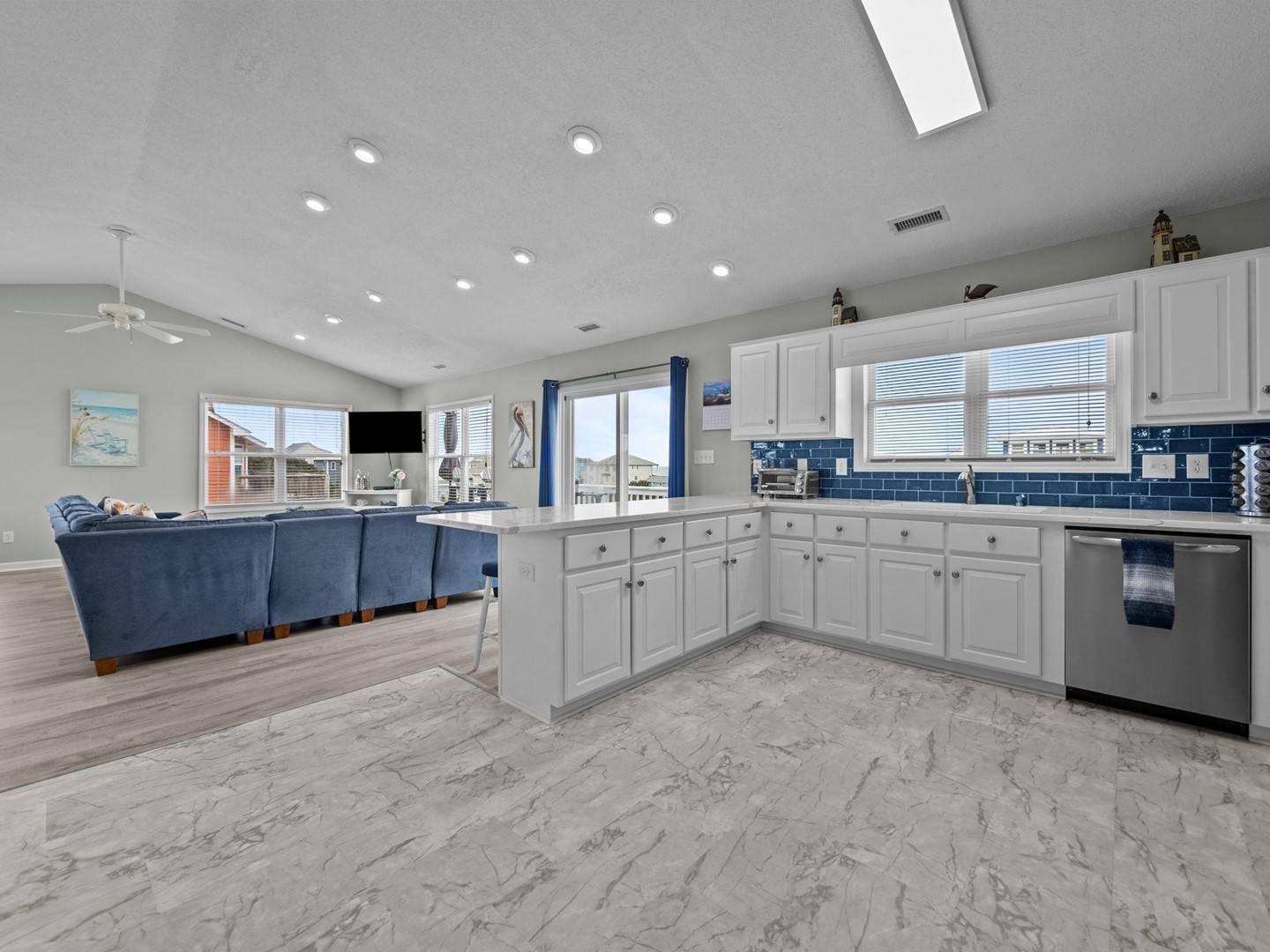 Your spacious kitchen features white cabinets, blue subway tile, and marble floors flowing into the cozy living room.