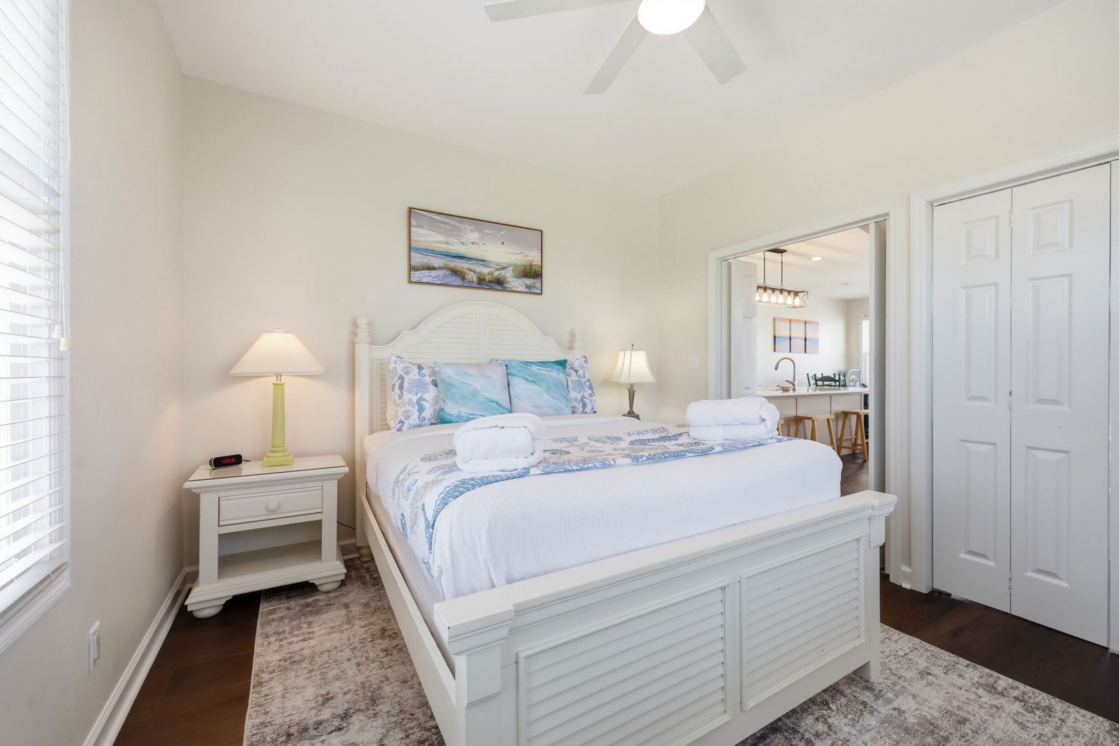 Unwind in your serene coastal-themed bedroom, featuring a plush bed dressed in soft blues and fresh linens, with airy vaulted ceilings and warm bedside lighting welcoming you home.