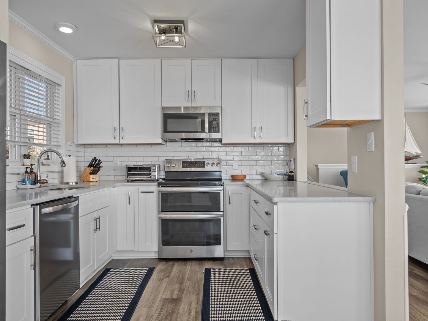 Your fully equipped kitchen awaits with pristine white cabinets, stainless steel appliances, and gleaming countertops for effortless meal preparation.